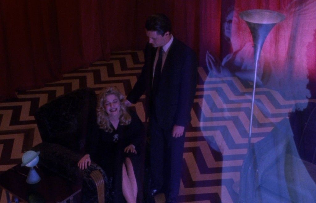 Laura Palmer seated in the Red Room with Cooper behind her as an angel appears