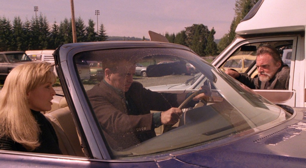 Philip Gerard leans from a truck shouting at Leland and Laura Palmer in their car
