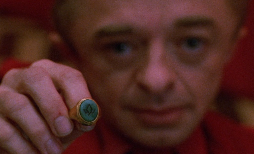 The green owl-cave ring held up in the Red Room - Man from Another Place behind